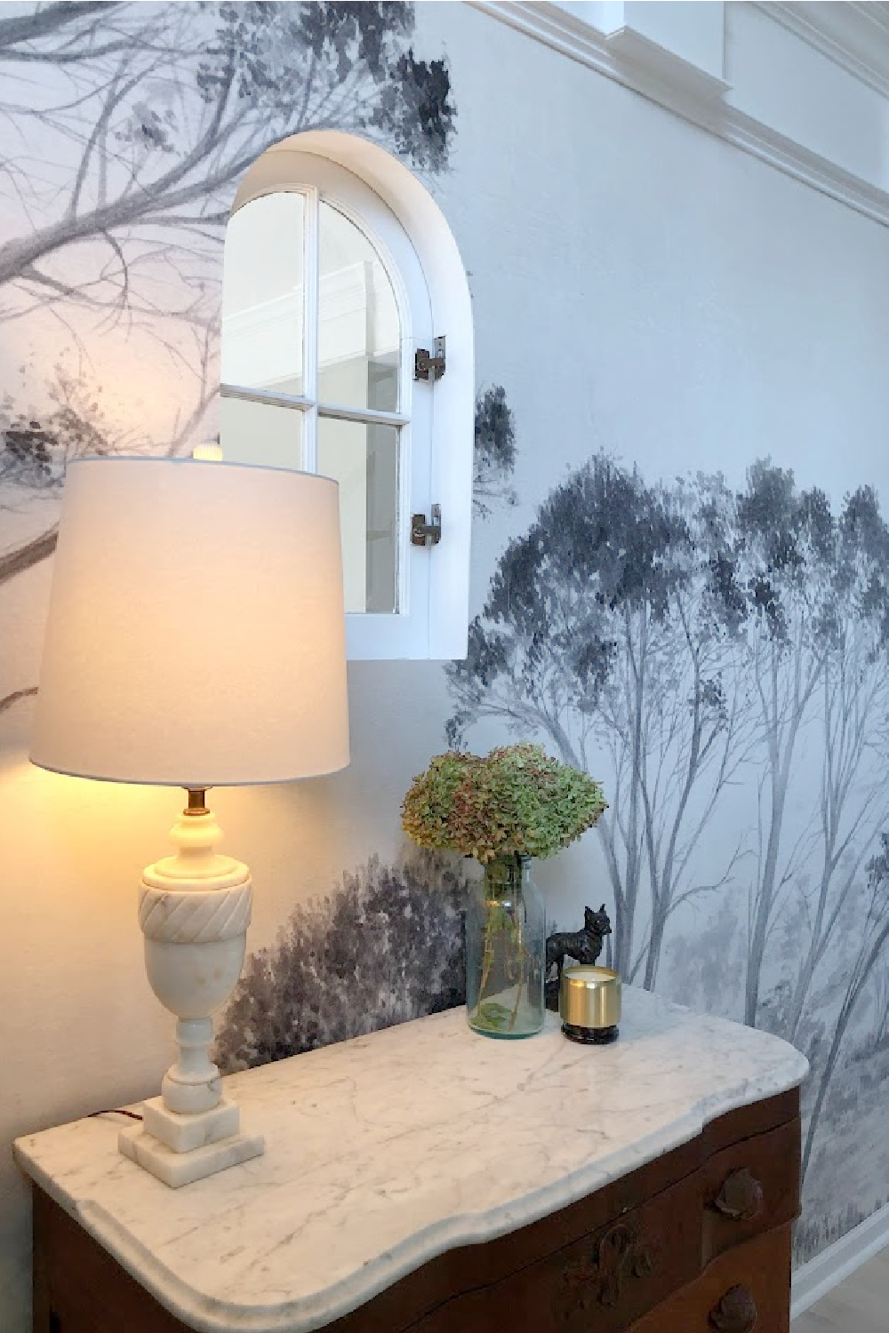 Tree mural wallpaper (Photowall) in our entry with interior arched window and marble topped chest - Hello Lovely Studio.