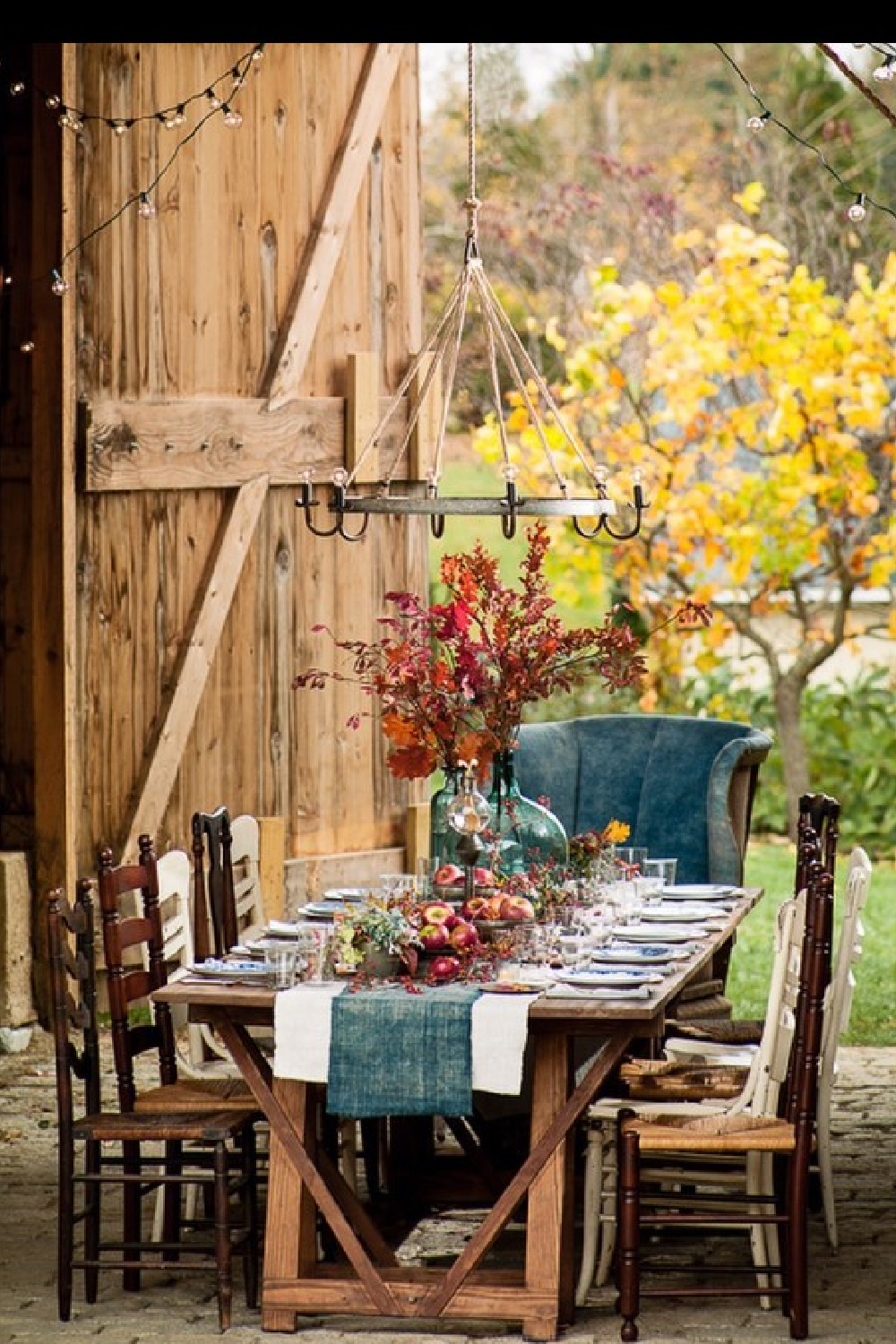 Thanksgiving tablescape with orange and blue in a lovely barn featured in Southern Living - Helen Norman. #thanksgivingtable #rustictablescape #falltablescape