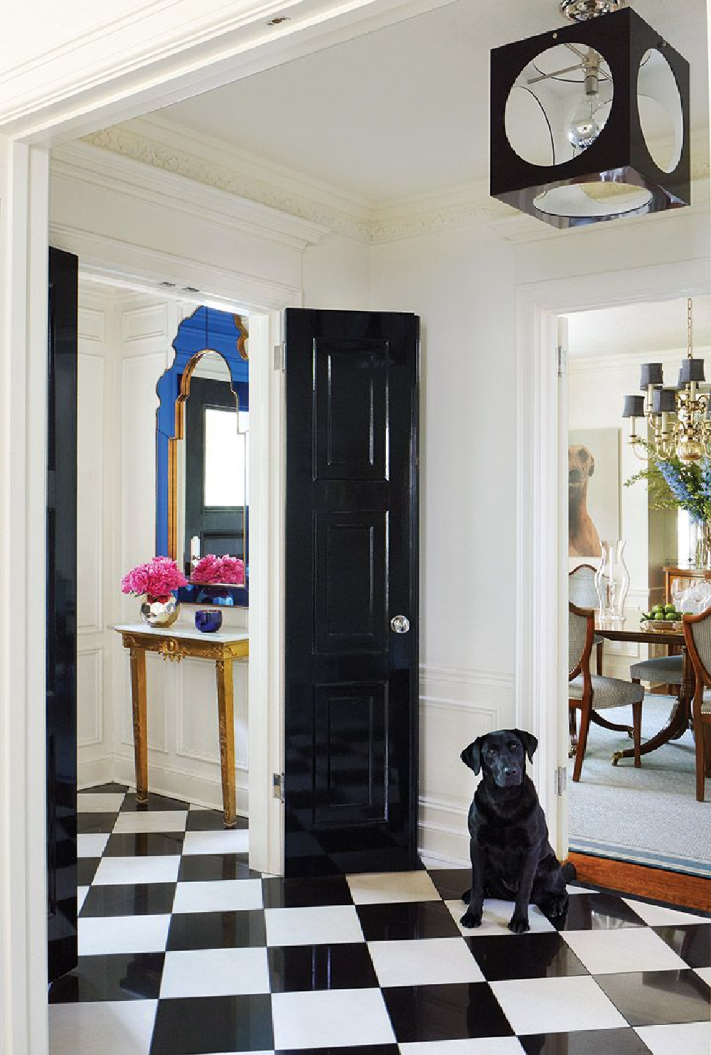 Black and white checkerboard floors and black doors lay the foundation for a timeless entry - design by Anne Hepfer in MOOD (Gibbs Smith, 2022). #modernenglishcountry #entry #blackandwhite