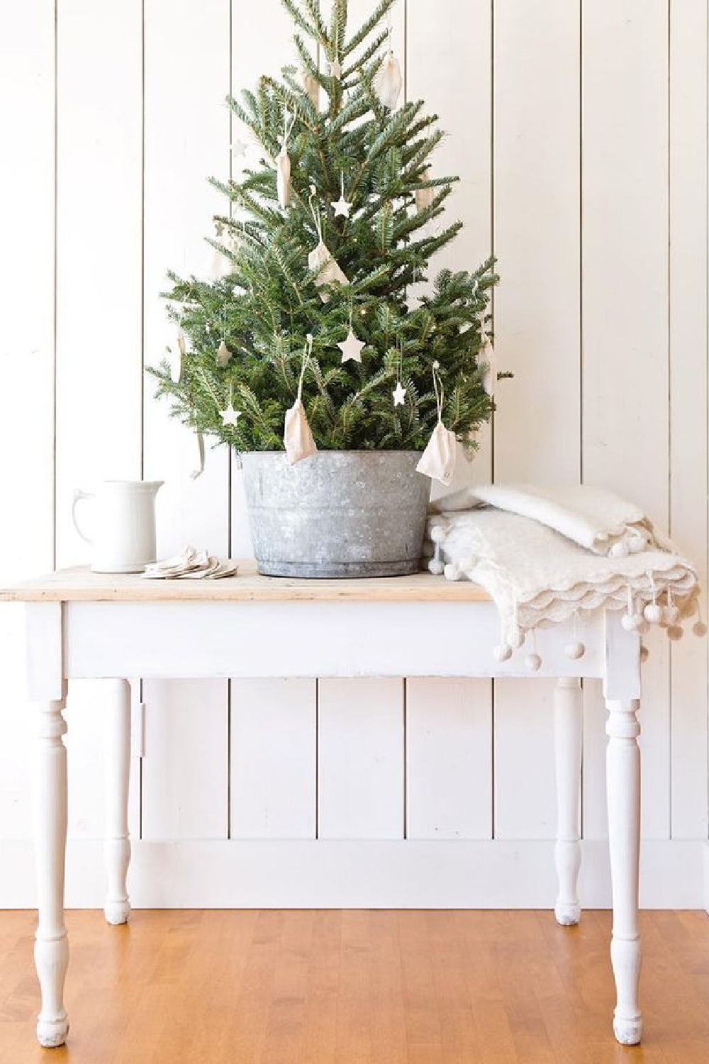 Farmhouse Christmas decor moment in a room with white shiplap, tree in galvanized pail and white farm table - A Rosy Note.