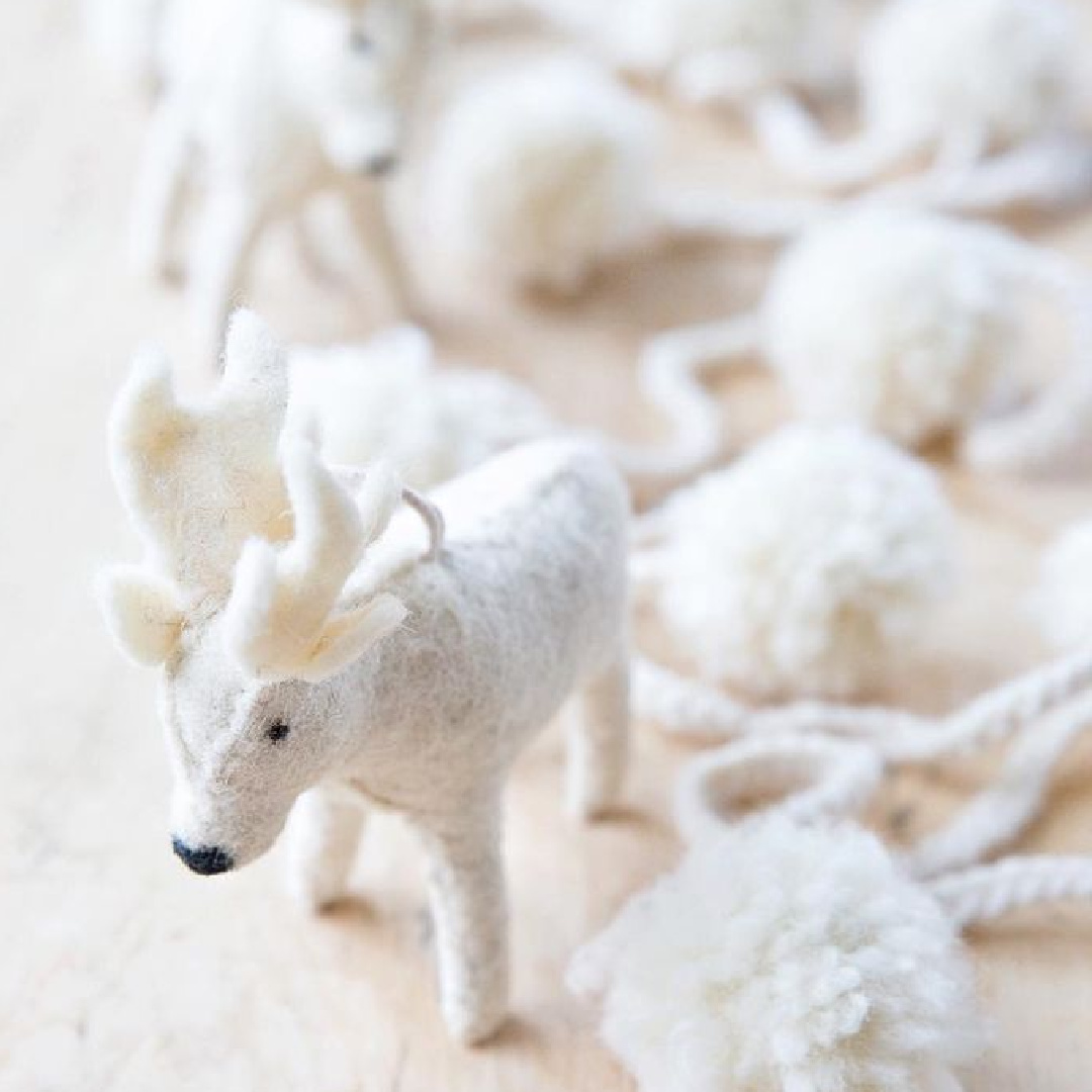 Adorable white felted wool moose and pom pom Christmas garland upon a rustic wood farm table - A Rosy Note.