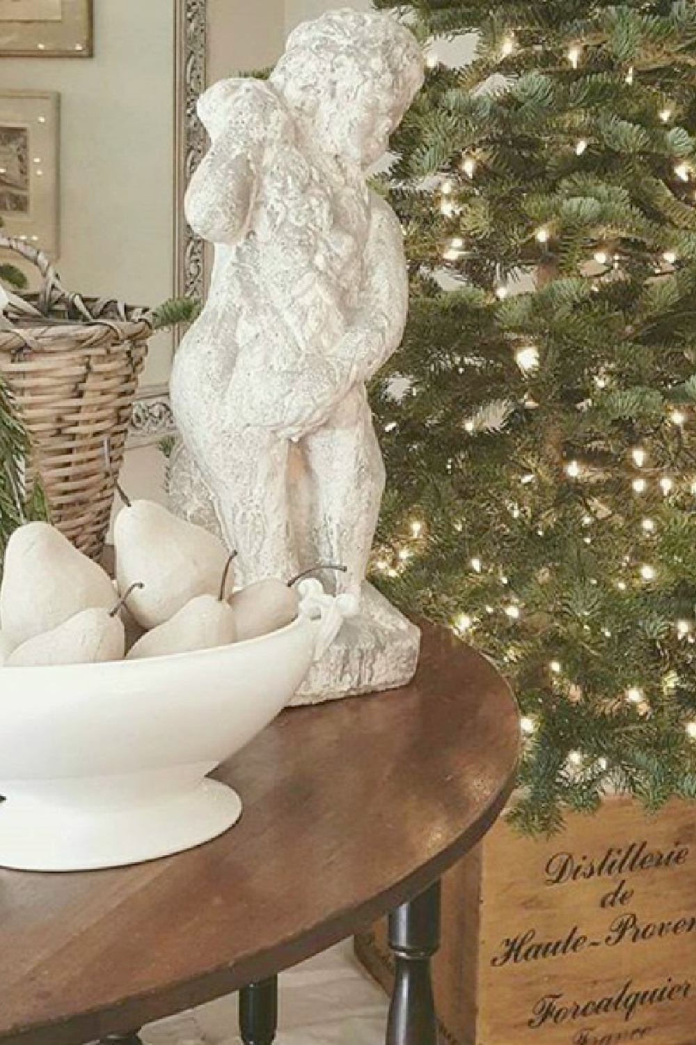 White bowl of pears on an elegant table near Christmas tree in a French country home with white sophisticated details and greenery - The French Nest Co Interior Design. #frenchcountry #frenchchristmas #christmasdecor #whitechristmasdecor