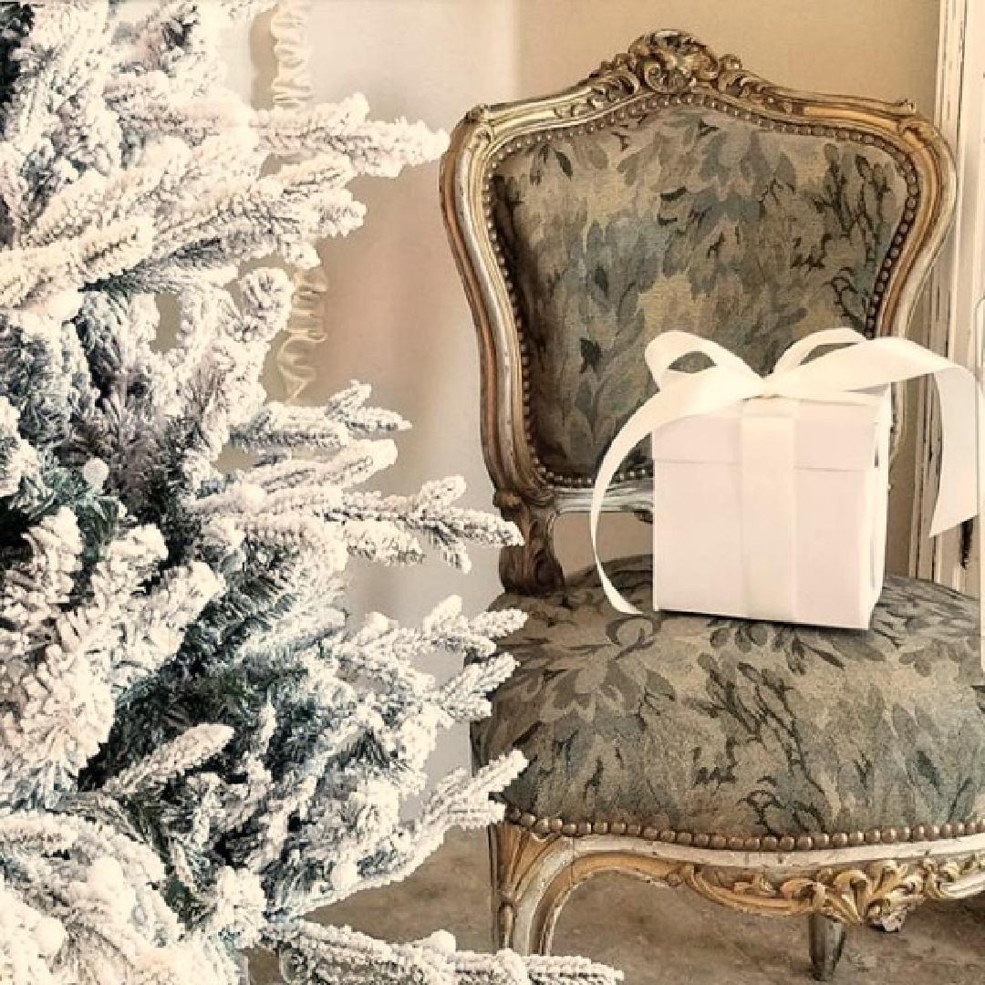 French chair near flocked Christmas tree is an elegant moment by The French Nest. #frenchcountry #frenchchristmas #christmasdecor #whitechristmasdecor