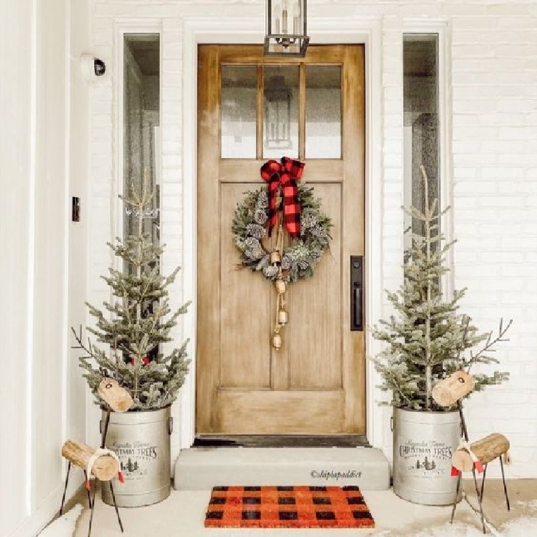 Farmhouse Christmas decorated porch with wreath, buffalo check red ribbon, gold bells, and wood reindeer - ShiplapAddict. #christmasporch #farmhousechristmas