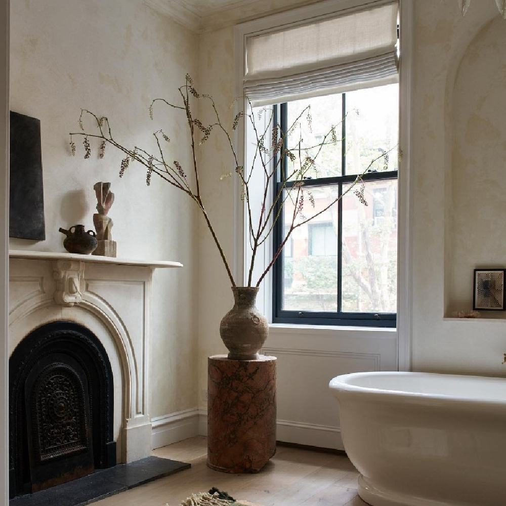 Serene luxurious minimal bath with antique fireplace and design by Eyeswoon.