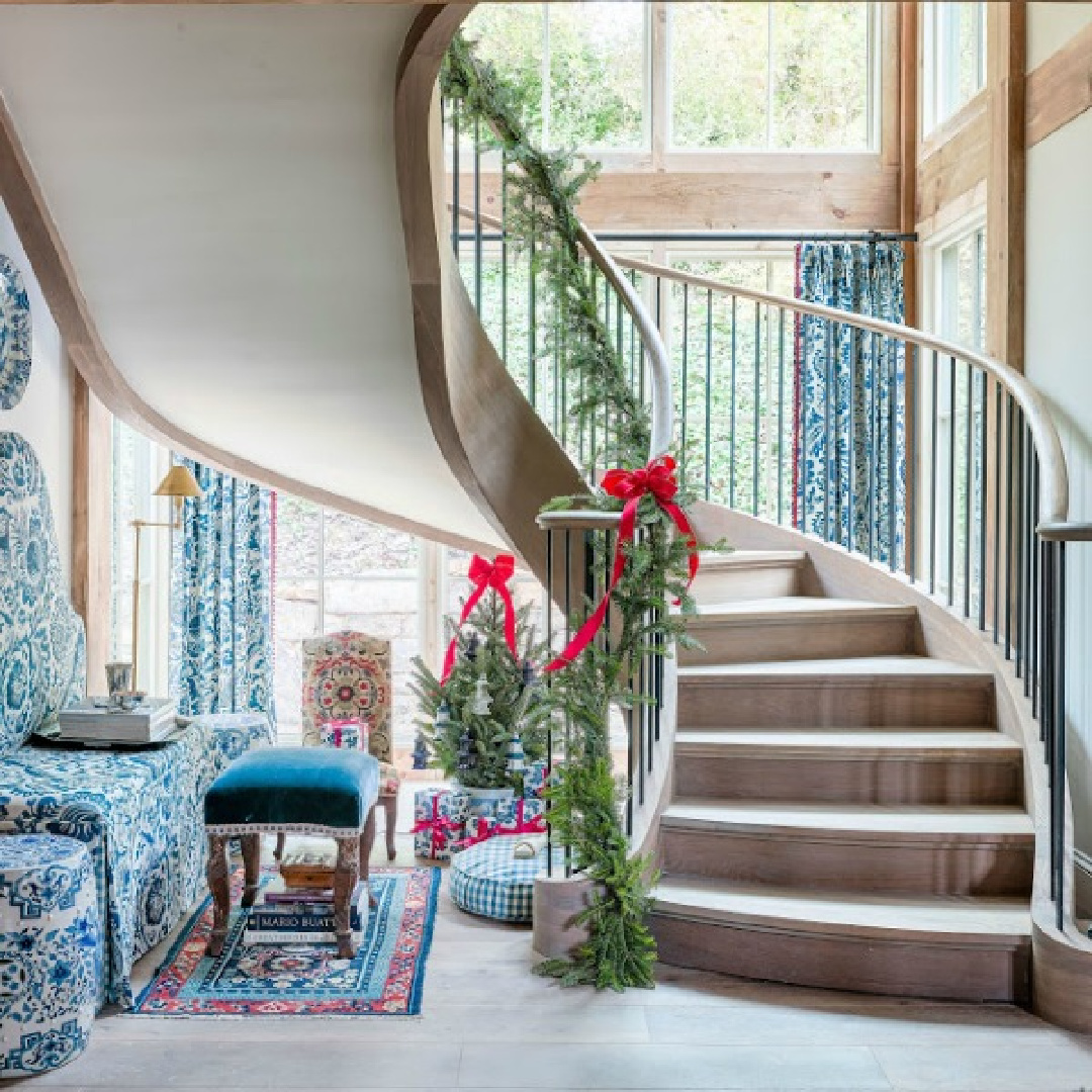 Magnificent curving staircase with Christmas garland in Atlanta Holiday Home 2019 with blue accents. #southernchristmas #christmasstaircase