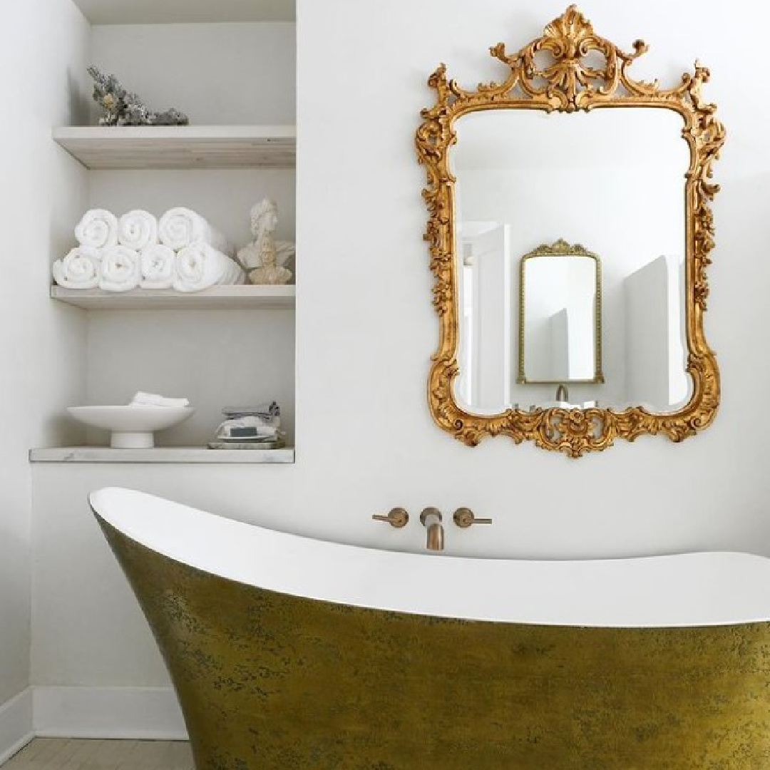 Elegant yet simple bath designed by Leanne Ford with gold soaking tub and ornate gilded mirror.
