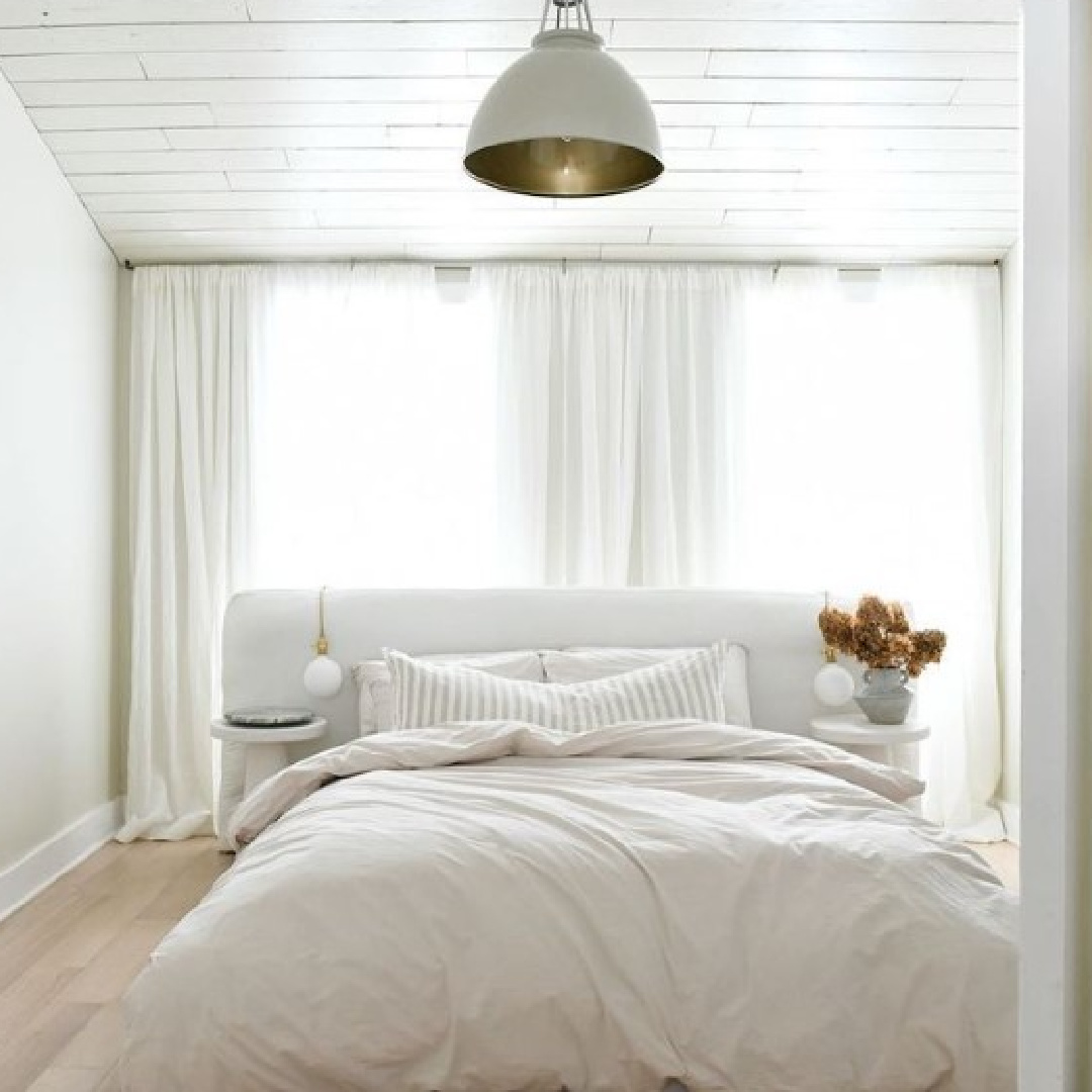 Modern rustic luxe white bedroom by Leanne Ford with bed in front of windows. #leanneford