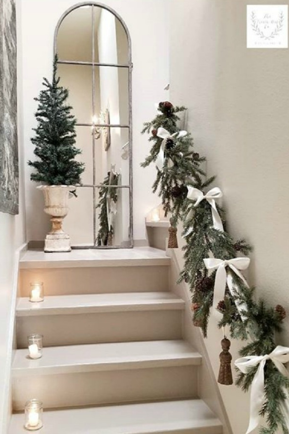 French country Christmas decorated staircase with garland and white ribbon on rail and candles on steps - The French Nest Co Interior Design. #frenchcountryholiday
