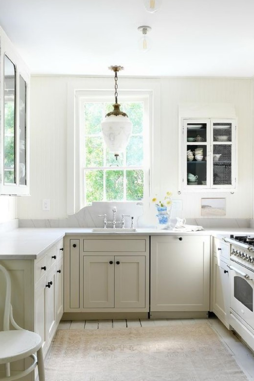 Leanne Ford Designed white serene kitchen with area rug and oversized pendant over sink.