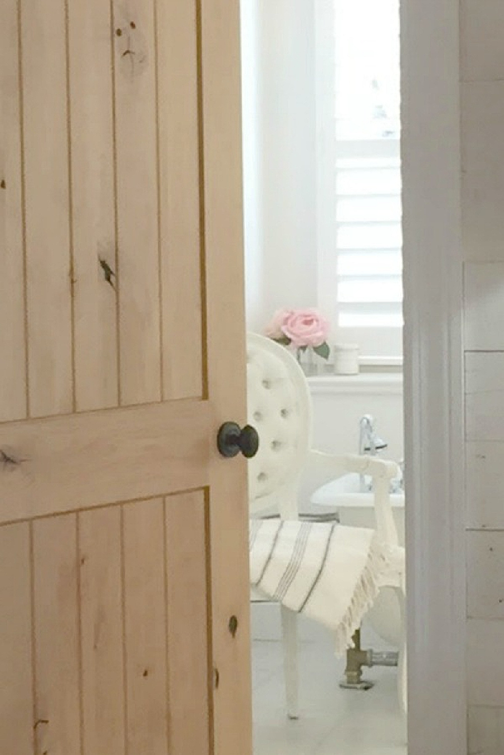 Knotty alder door (left natural with no stain) to our French country white bathroom with Louis chair and clawfoot tub. #frenchcountry #romanticbedroom #alderdoor