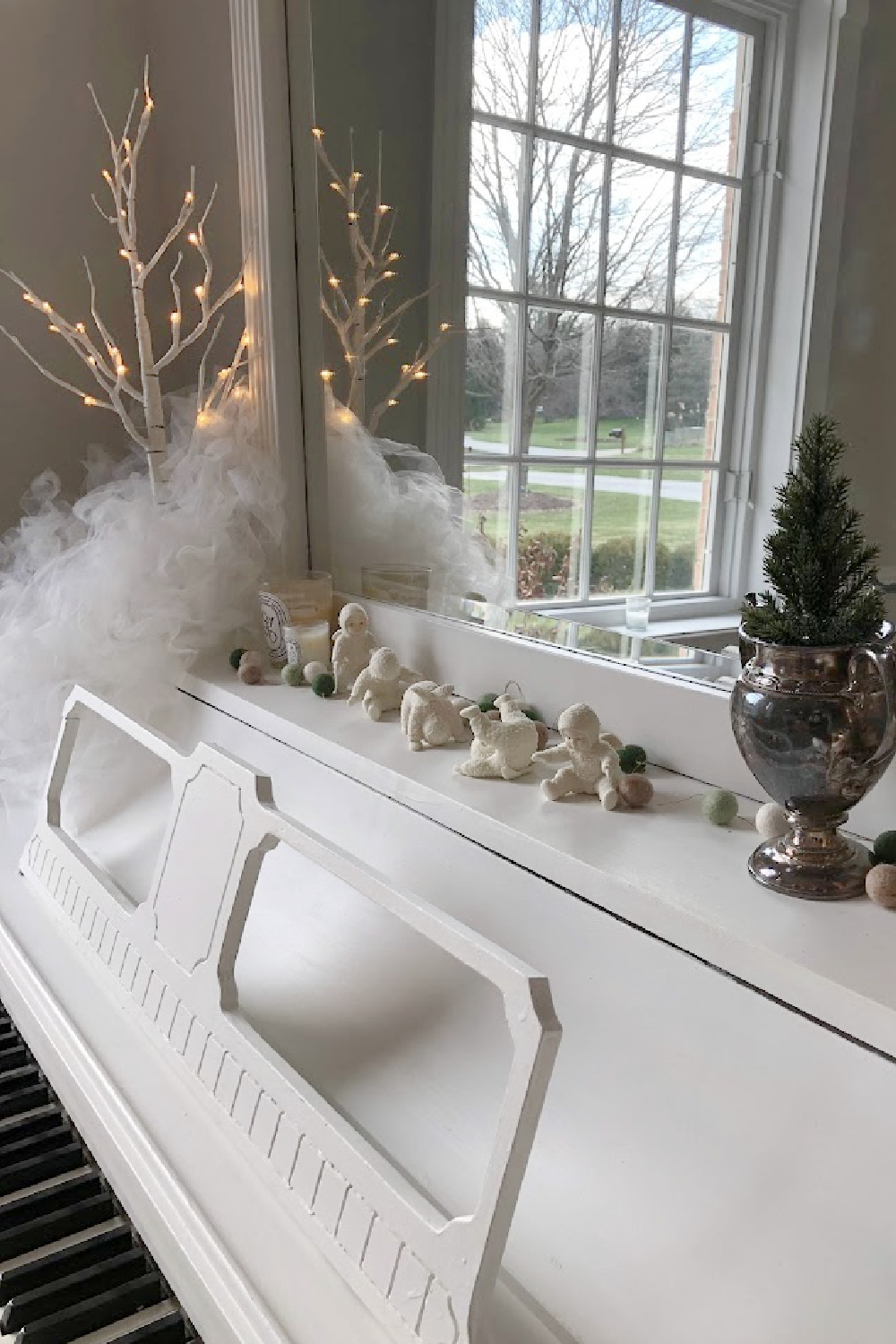 White piano and Christmas decorations including snowbabies and little tree with fairy lights - Hello Lovely Studio.