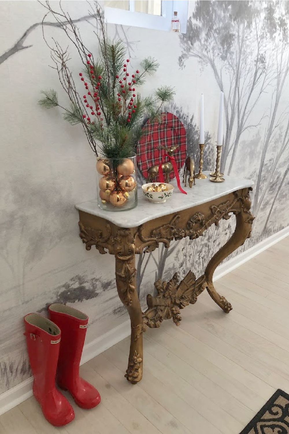 French antique console table decorated for Christmas in entry with grisaille tree wallpaper mural - Hello Lovely Studio. #modernfrench #frenchchristmas