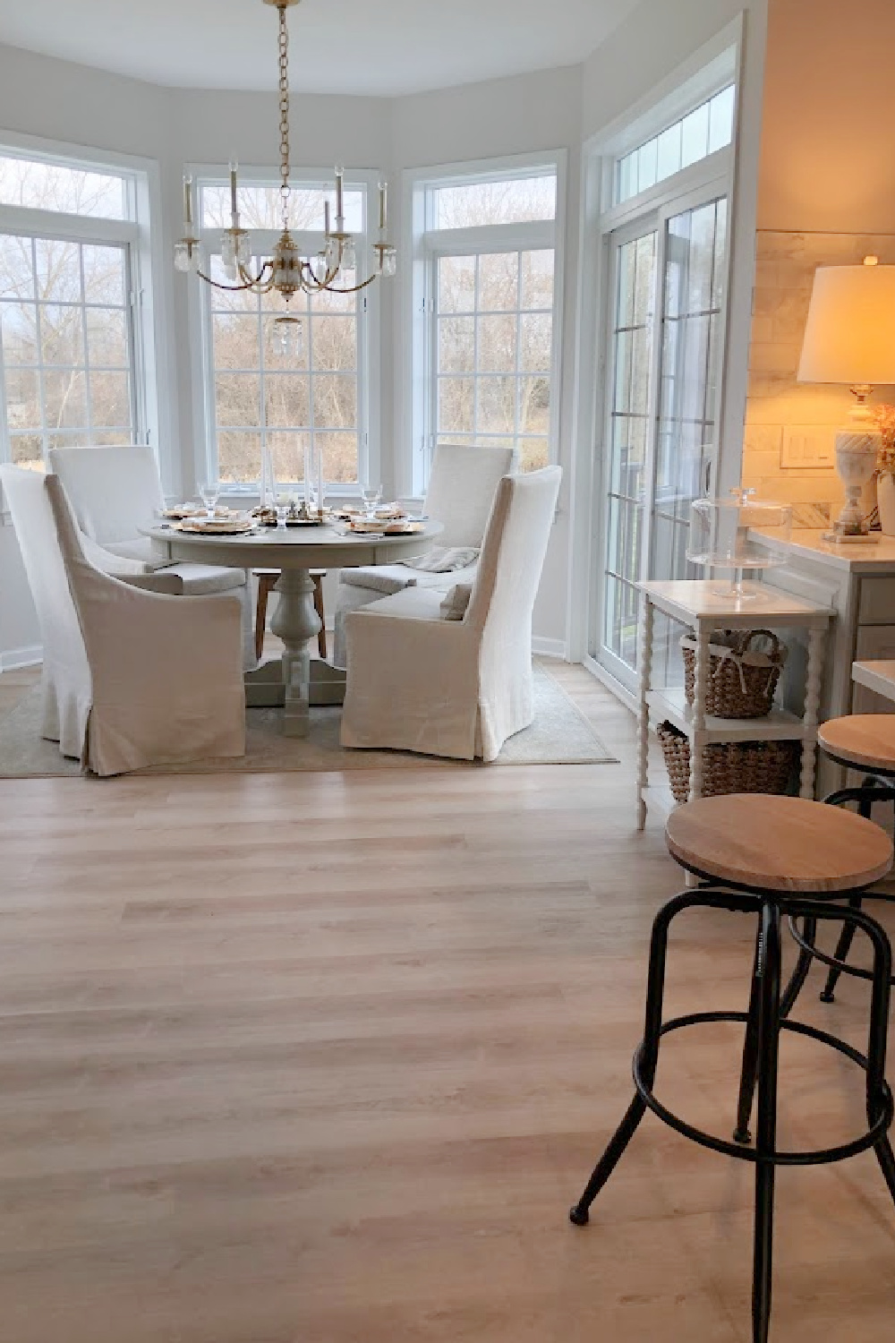 Breakfast nook with gilded chandelier and bay of windows in our renovated kitchen - Hello Lovely Studio.