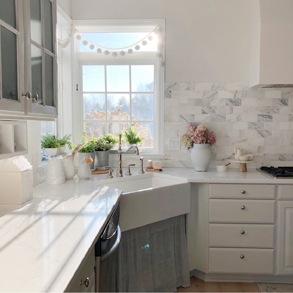 Pom pom garland at the kitchen sink window - Hello Lovely Studio. #paviliongray #graykitchen #calacattagoldmarble