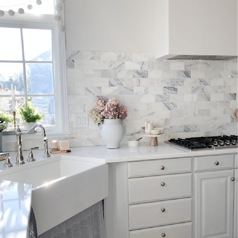 Pom pom garland at the kitchen sink window - Hello Lovely Studio. #paviliongray #graykitchen #calacattagoldmarble