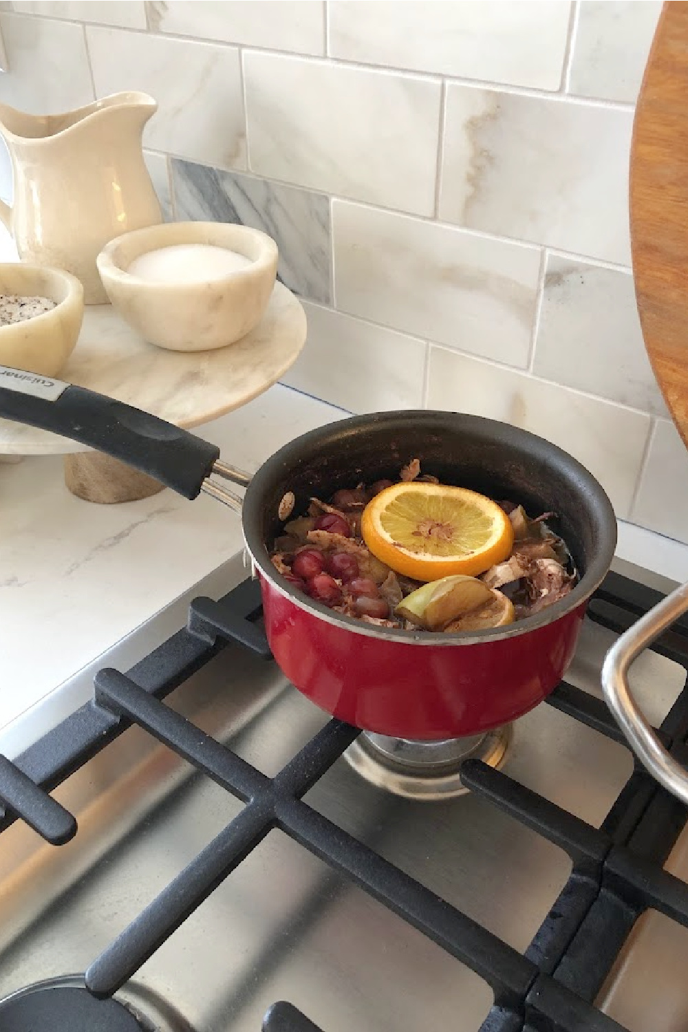 Citrus and spices simmering on the cooktop for Thanksgiving - Hello Lovely Studio. The countertop is Viatera Muse, and the backsplash is calacatta gold marble subway tile.