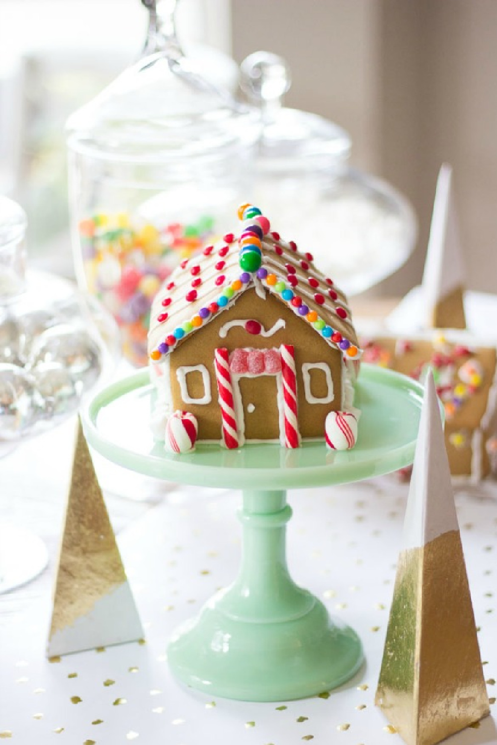 Sweet little gingerbread house cottage on a jadeite cake pedestal - Design Improvised. #gingerbreadhouse #christmasdiy #holidaybaking