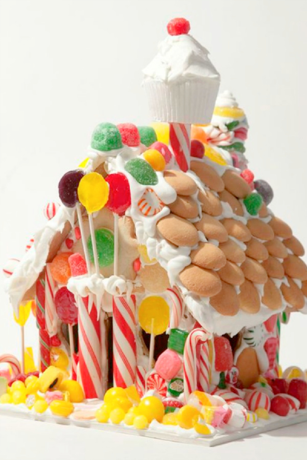 Cupcake chimney on a fanciful candy house decorated with vanilla wafers. #gingerbreadhouse #christmasbaking #holidaydiy