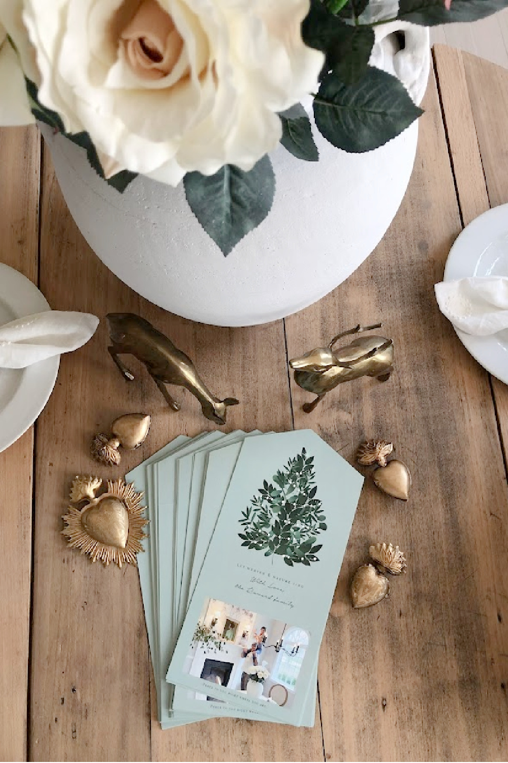 Minted photo Christmas card (Heaven and Nature Sing foldable design with perforated edge to remove photo) on dining room table with gold sacred milagros and vintage brass deer - Hello Lovely Studio. #mintedchristmascard