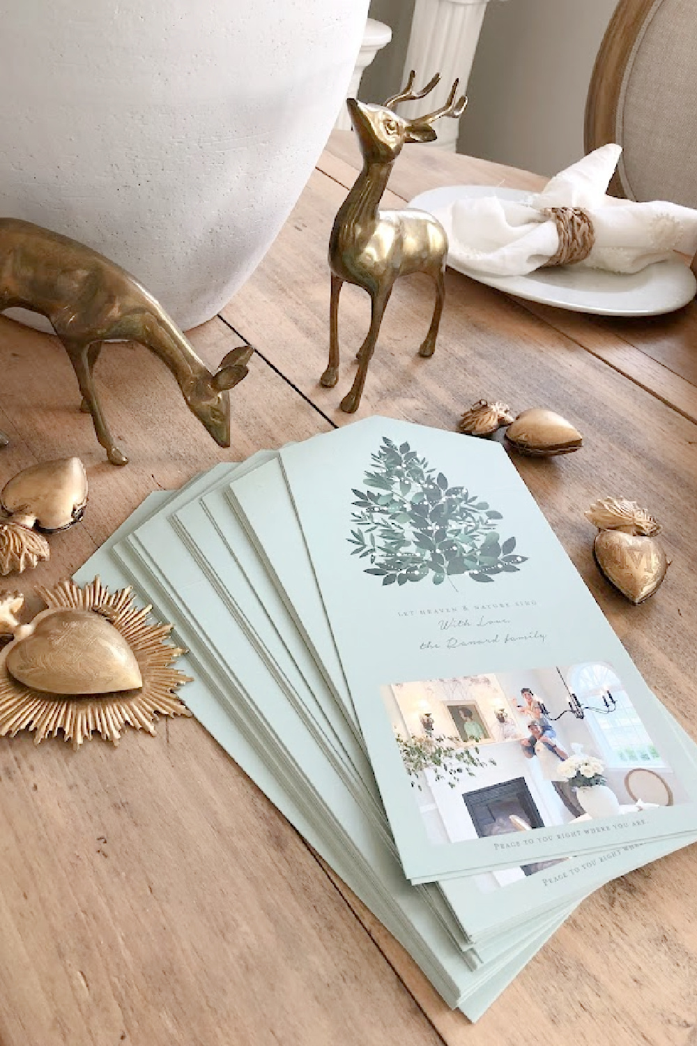 Minted photo Christmas card (Heaven and Nature Sing foldable design with perforated edge to remove photo) on dining room table with gold sacred milagros and vintage brass deer - Hello Lovely Studio. #mintedchristmascard