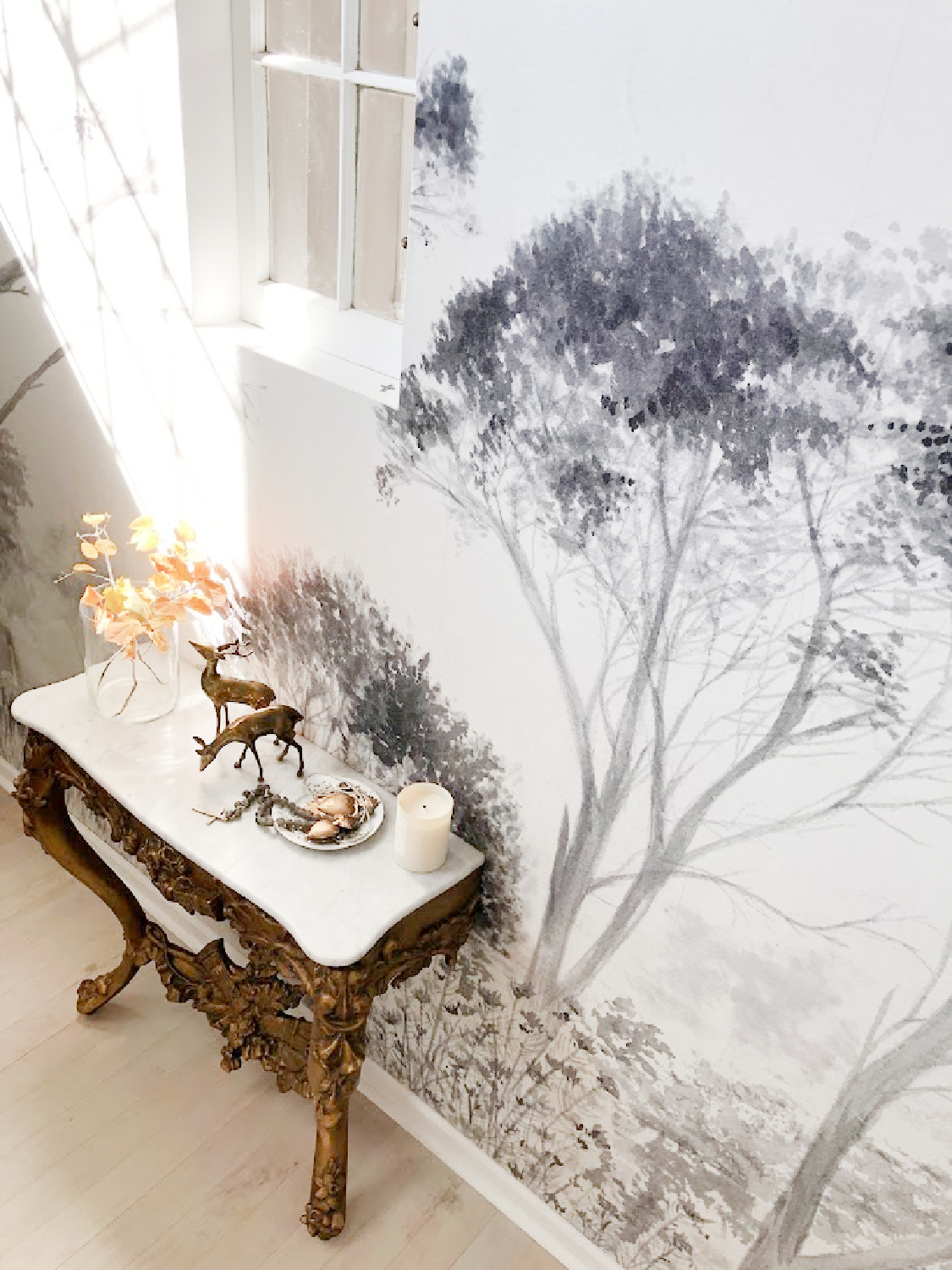 Antique French console with marble top in renovated entry with tree wallpaper mural - Hello Lovely Studio.