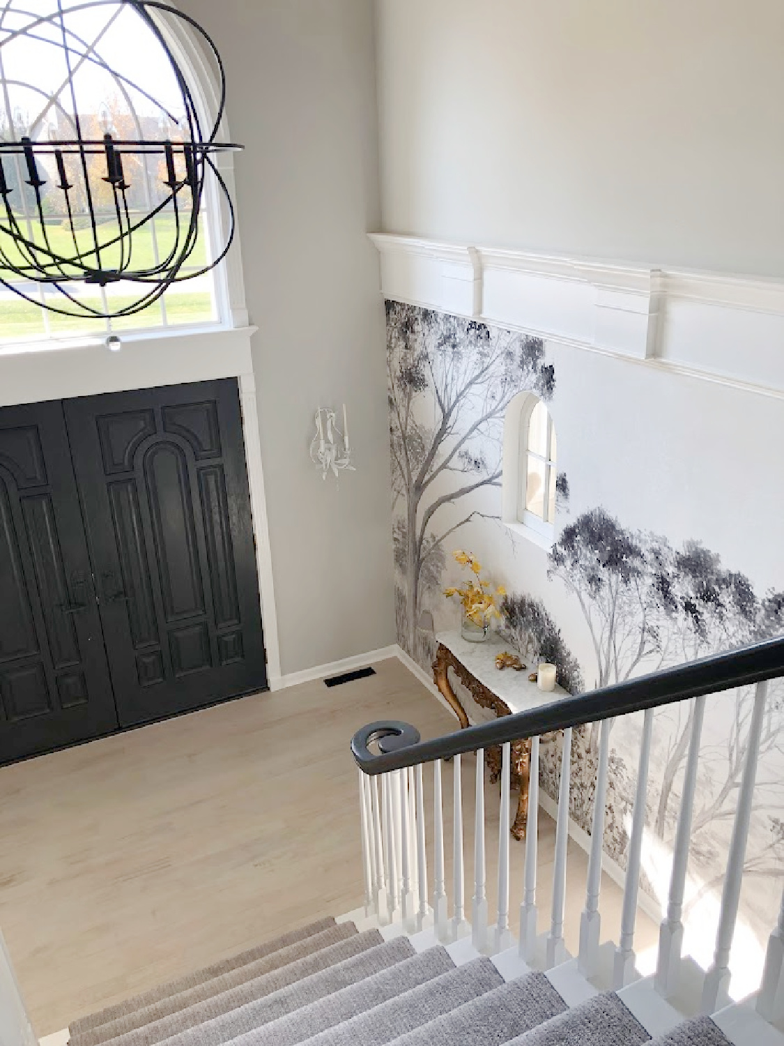 Renovated entry with dark gray doors (SW Carbonized), walls painted SW Repose Gray, tree mural (Photowall), and greyed oak hardwoods - Hello Lovely Studio.