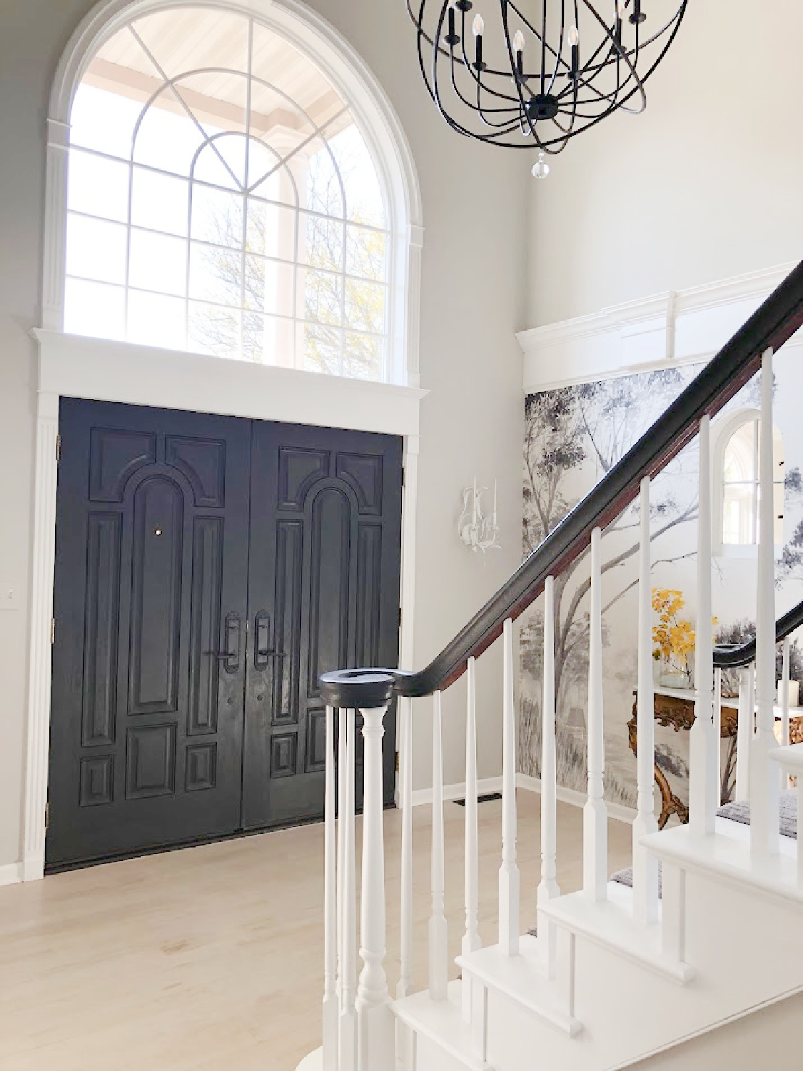 Renovated entry with dark gray doors (SW Carbonized), walls painted SW Repose Gray, tree mural (Photowall), and greyed oak hardwoods - Hello Lovely Studio.