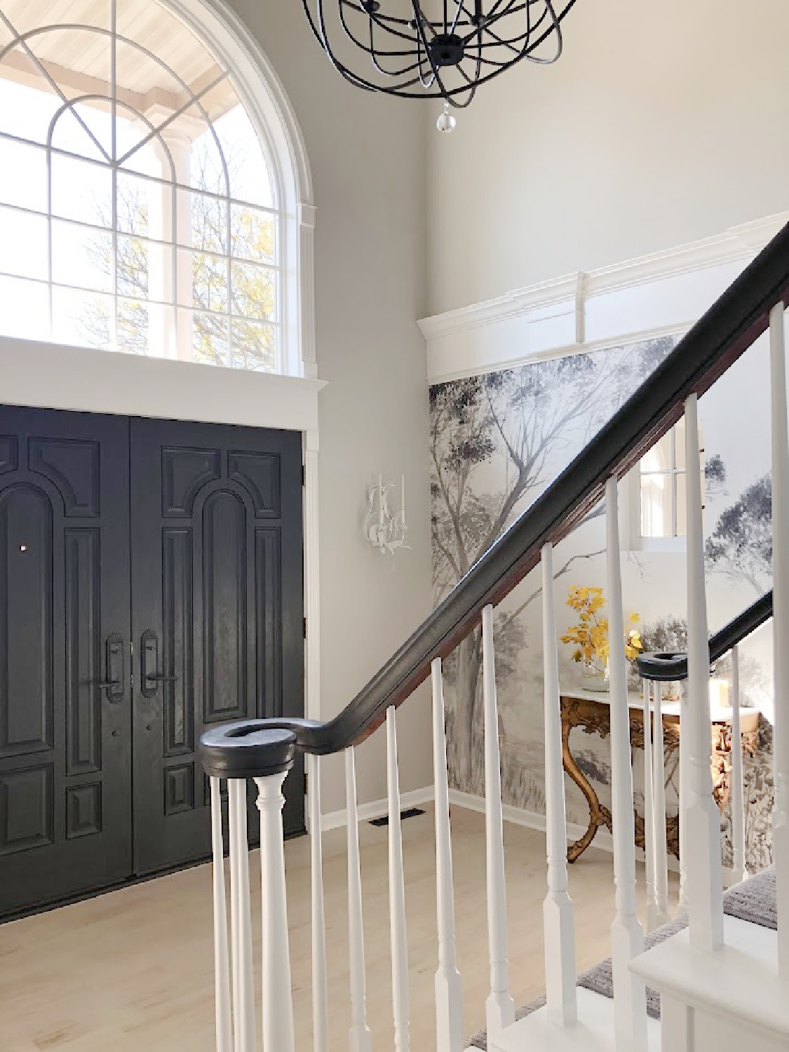 Renovated entry with dark gray doors (SW Carbonized), walls painted SW Repose Gray, tree mural (Photowall), and greyed oak hardwoods - Hello Lovely Studio.