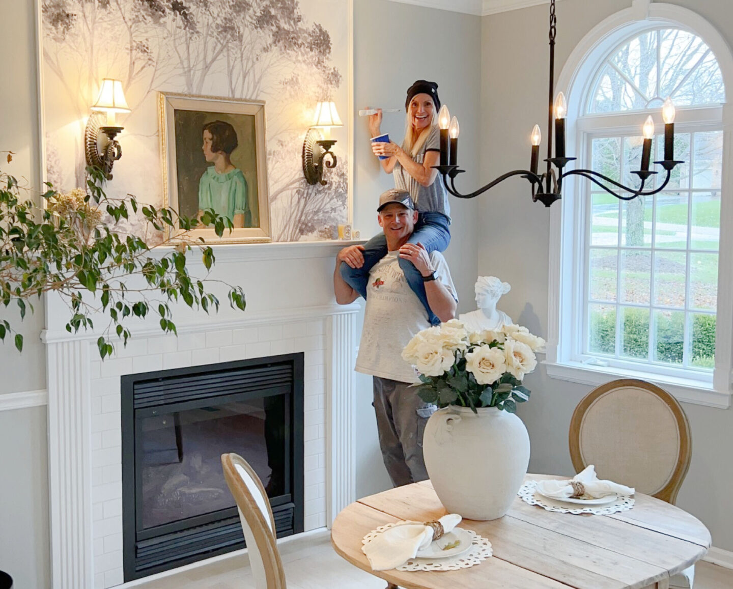 Michele on husband's shoulders painting fireplace trim - Hello Lovely Studio.