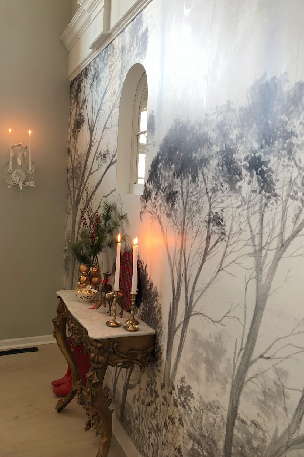 Holiday decor in our entry and dining room which feature a wallpapered tree mural, light grey stained floors, and a gentle quiet palette of serene hues - Hello Lovely Studio. #elegantchristmas #modernfrenchchristmas