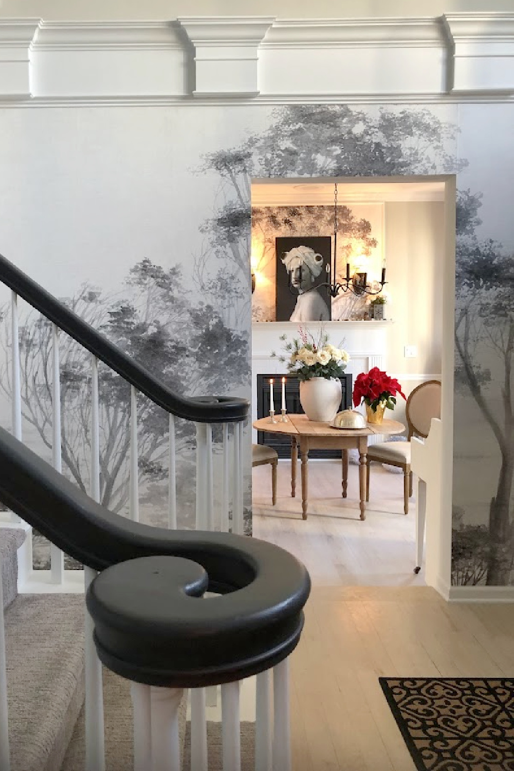 Holiday decor in our entry and dining room which feature a wallpapered tree mural, light grey stained floors, and a gentle quiet palette of serene hues - Hello Lovely Studio. #elegantchristmas #modernfrenchchristmas
