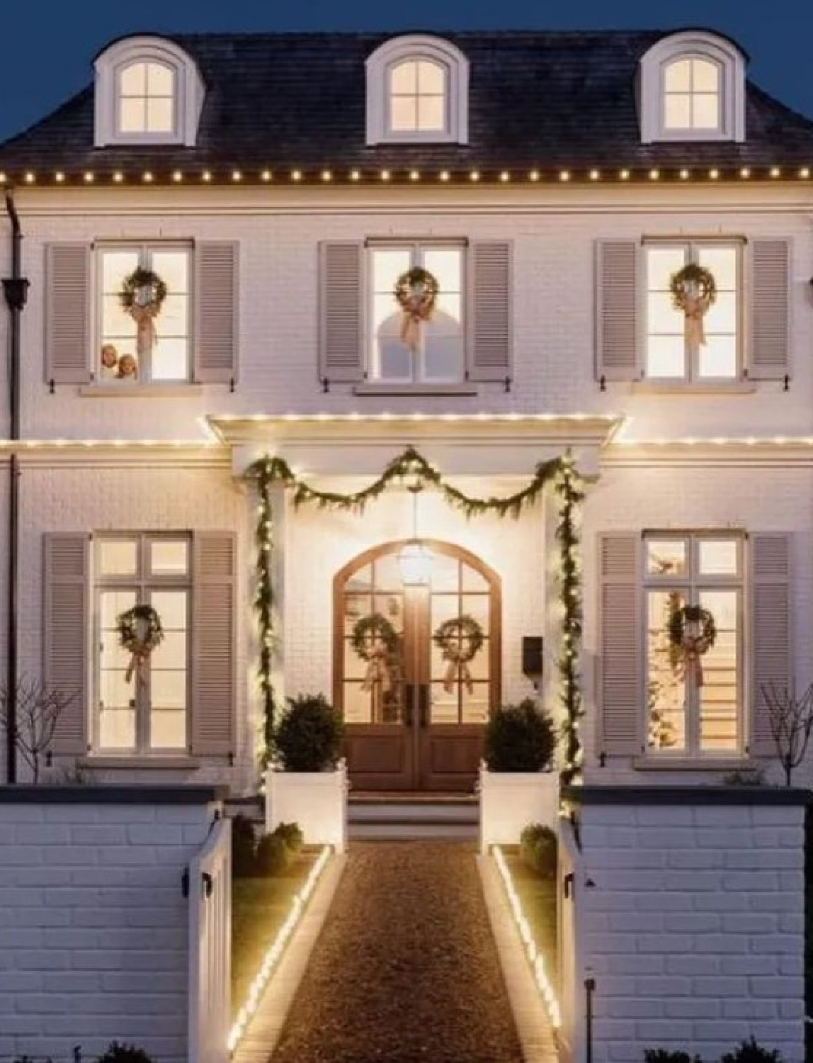 Heartwarming Christmas house exterior with French country architecture and wreaths in windows - @jennymartindesign for @lee_kristine. Photo: @platinumhdstudios. #frenchcountrychristmas