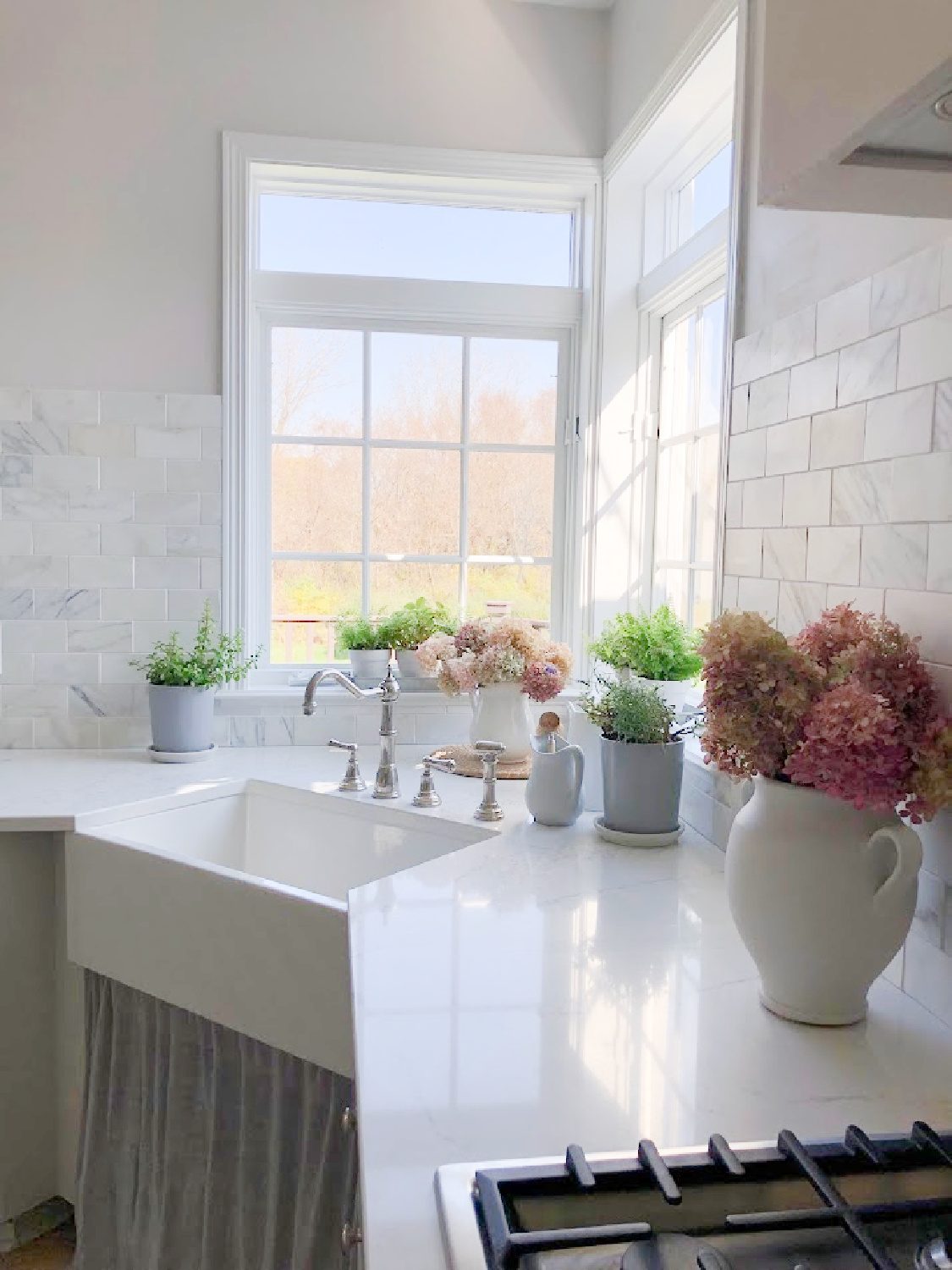 Hello Lovely's corner farm sink with linen skirt, Viatera Muse quartz counters, and SW Eider White walls.