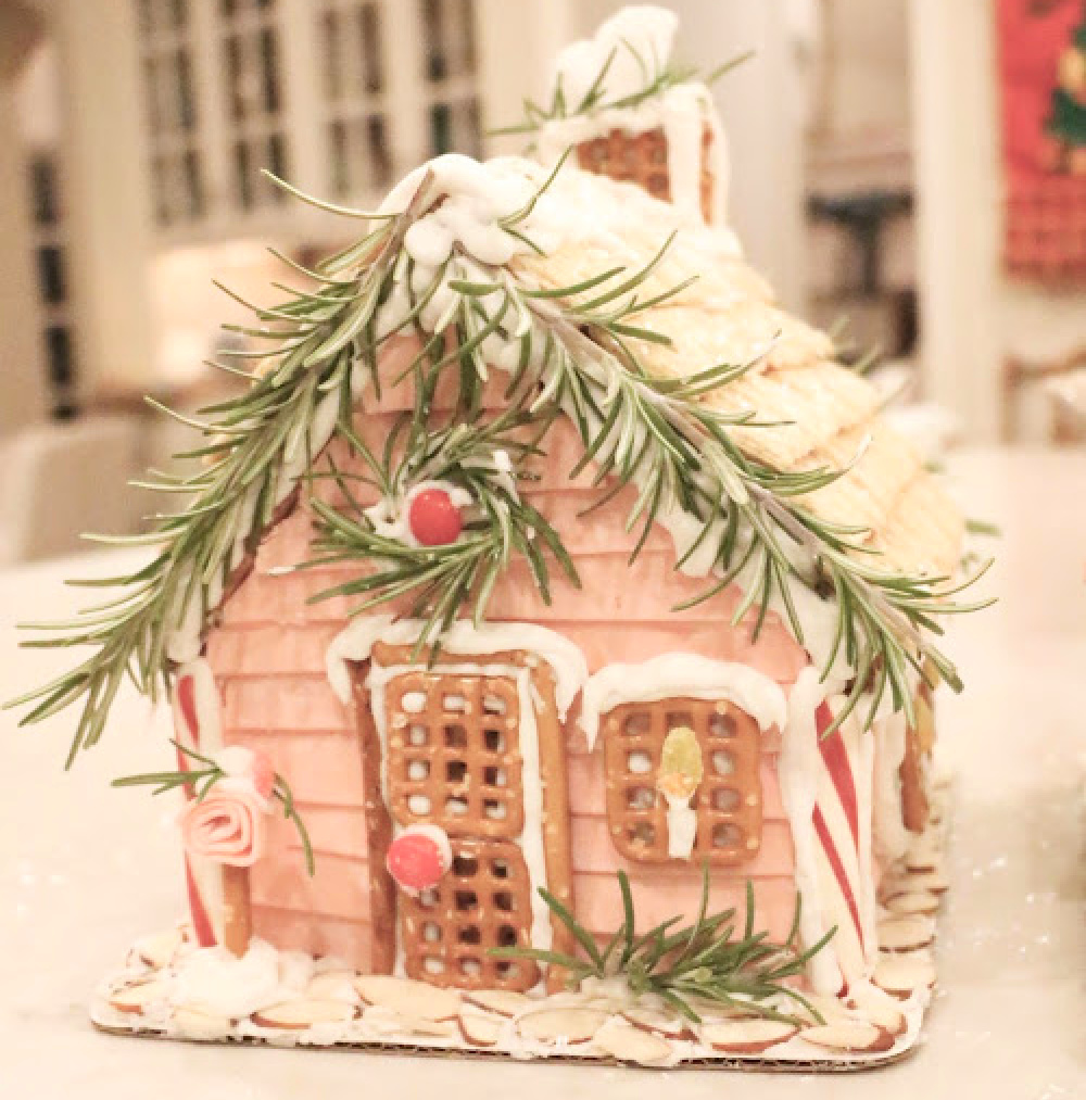 Charming and whimsical pink gingerbread house with rosemary, pretzel windows, and bubblegum tape - Eleven Gables. #gingerbreadhouses #pinkchristmas