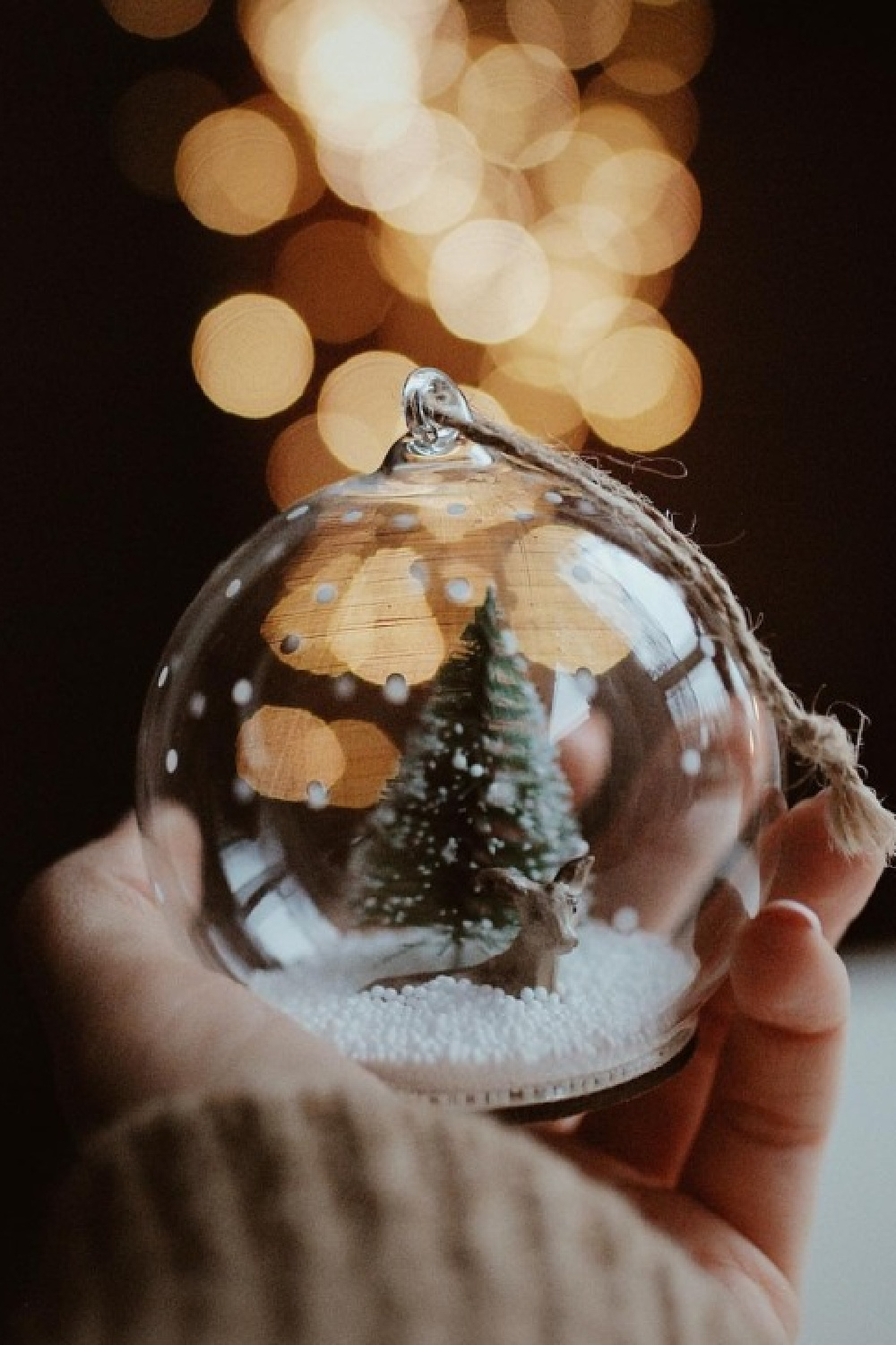 Cozy Christmas image with hand holding small snow globe with tiny tree @ChristmasXmas. #cozychristmas #snowglobes #wintervibes