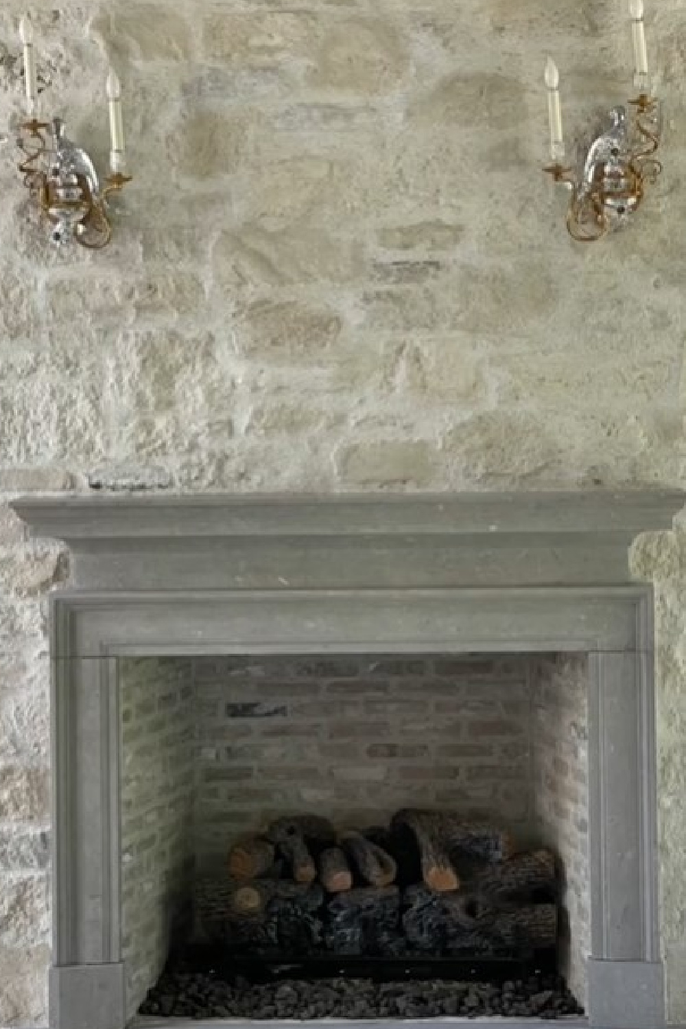 Old World style fireplace and stone surround with elegant sconces - Brooke Giannetti of Velvet and Linen.