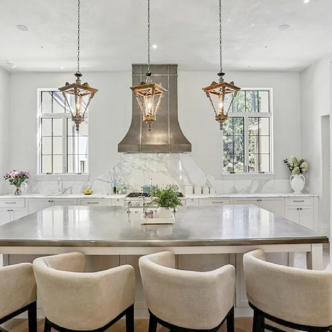 Luxurious modern French kitchen with a trio of French lanterns over island and beautiful sculptural range hood. #modernfrenchkitchen #frenchcountrykitchens