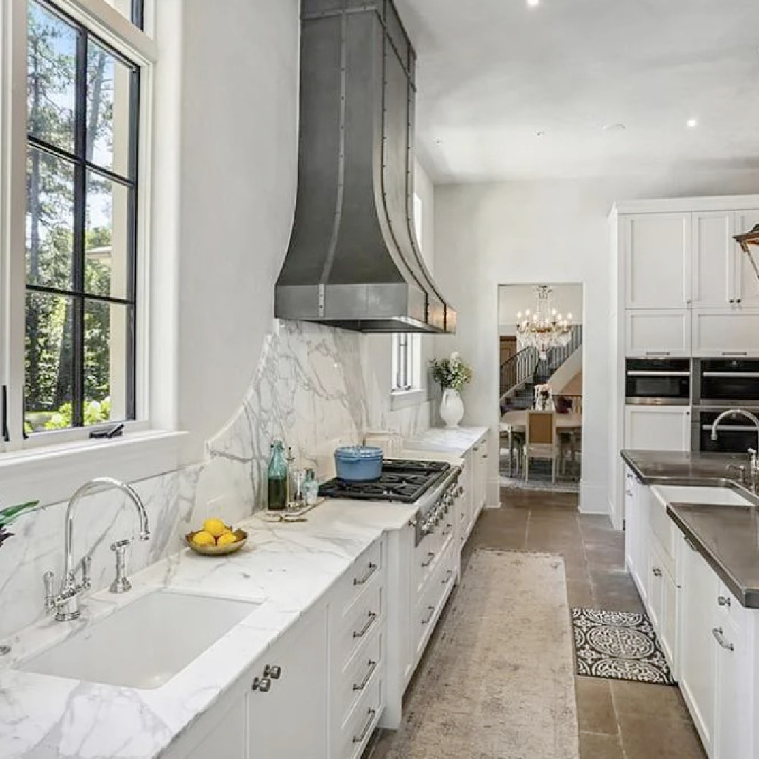 Luxurious modern French kitchen with a trio of French lanterns over island and beautiful sculptural range hood. #modernfrenchkitchen #frenchcountrykitchens