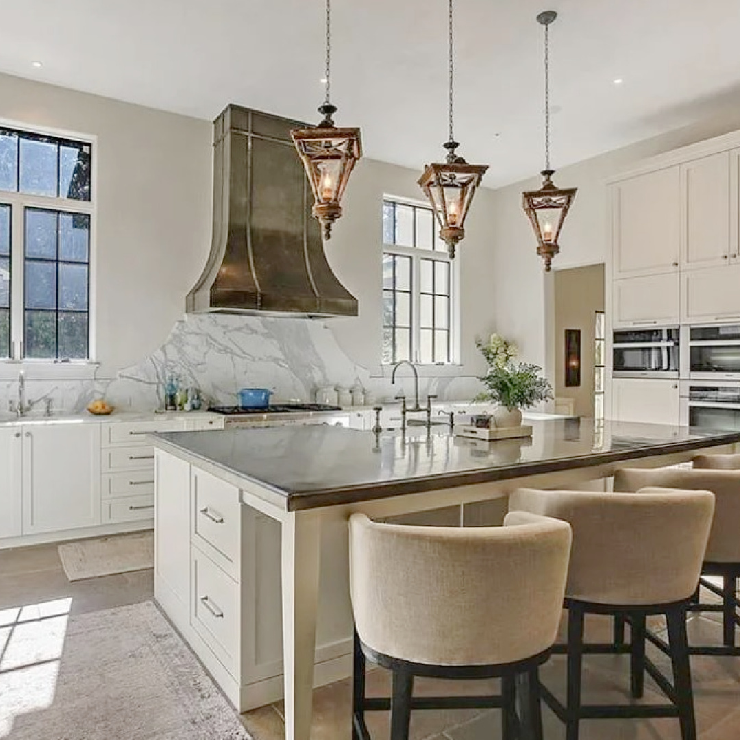 Luxurious modern French kitchen with a trio of French lanterns over island and beautiful sculptural range hood. #modernfrenchkitchen #frenchcountrykitchens