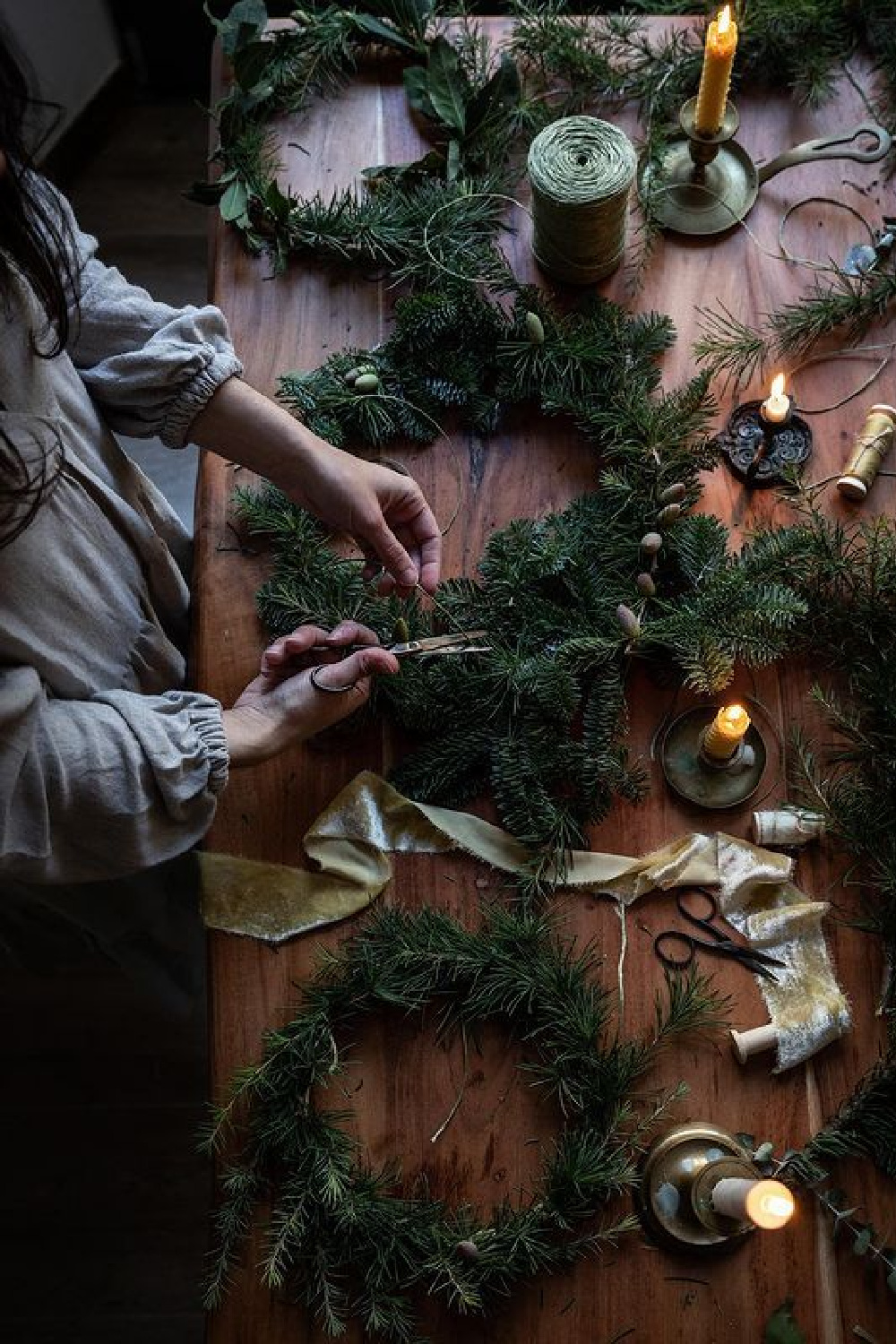 Wreath making on a farm table with candles - @twiggstudios. #christmaswreaths