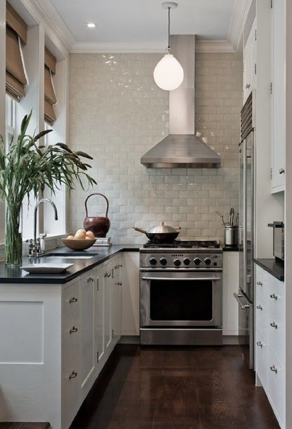 Kevin Dakan kitchen via Remodelista. Small white classic cottage kitchen with glazed tile statement wall and dark counters. #smallkitchens #ushape #kitchendesign