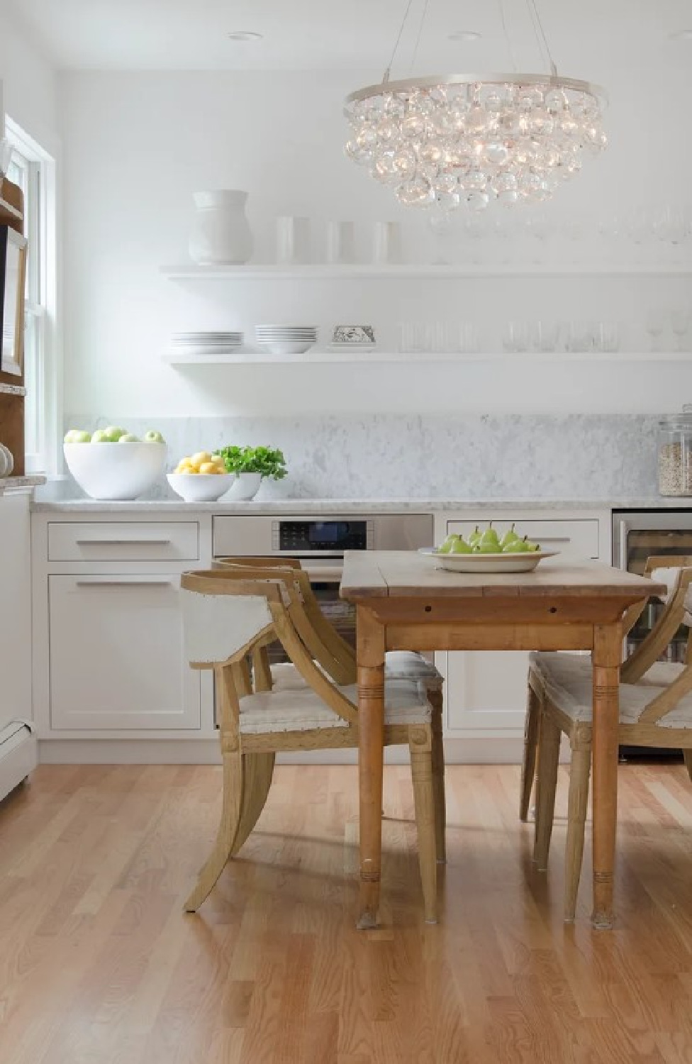 Chic modern country white kitchen with vintage accents, white marble, wood floors, and design by Kelly McGuill. Photo by Tamara Flanagan. #warmwhitekitchens