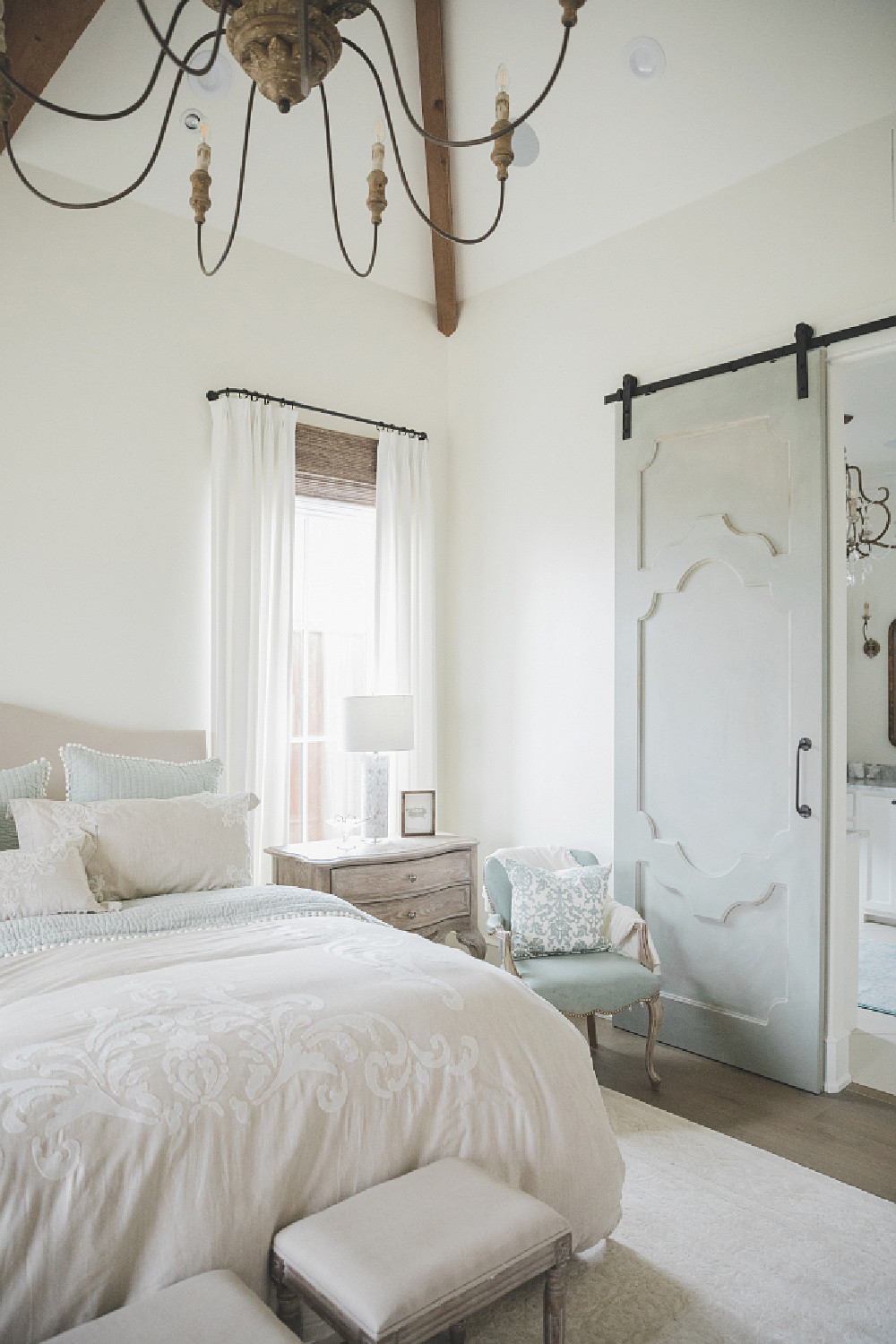 French country farmhouse bedroom with Duck Blue barn door and Sherwin Williams Alabaster paint color on walls. Brit Jones Design.