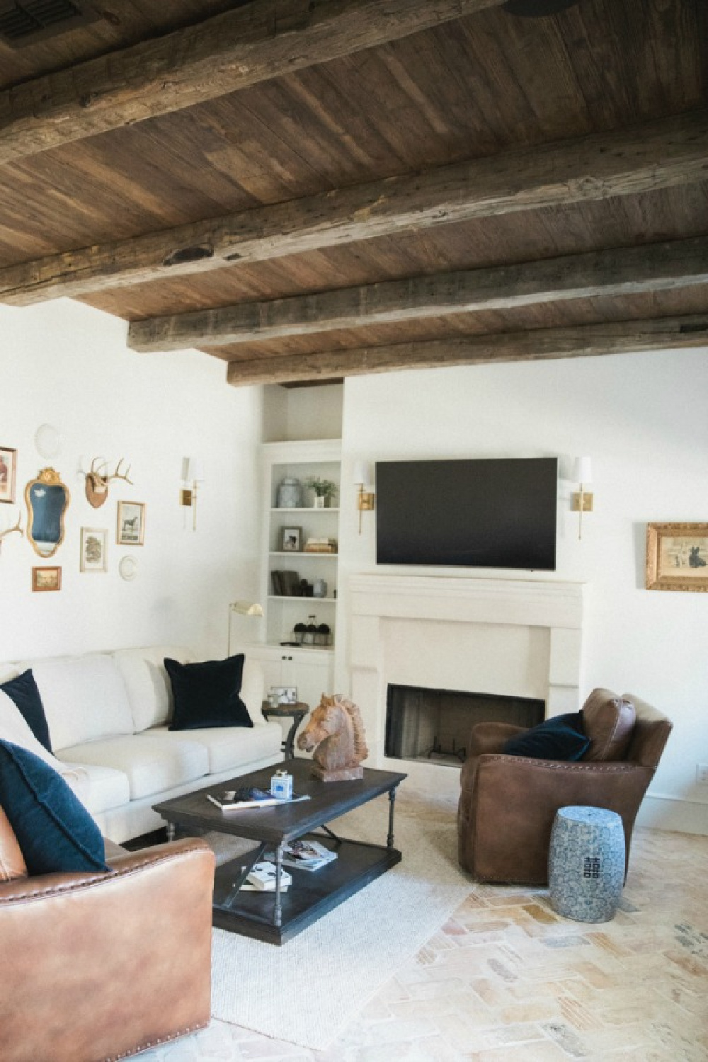 Rustic den with reclaimed dark wood ceiling, leather chair, and Sherwin Williams Alabaster paint color on walls. Brit Jones Design.