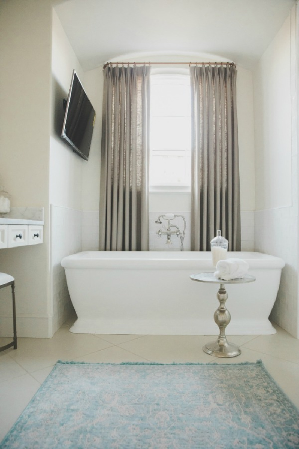 Serwin Williams Alabaster paint on walls. Elegant French country white bathroom with freestanding tub and drapes at window. Brit Jones Design.