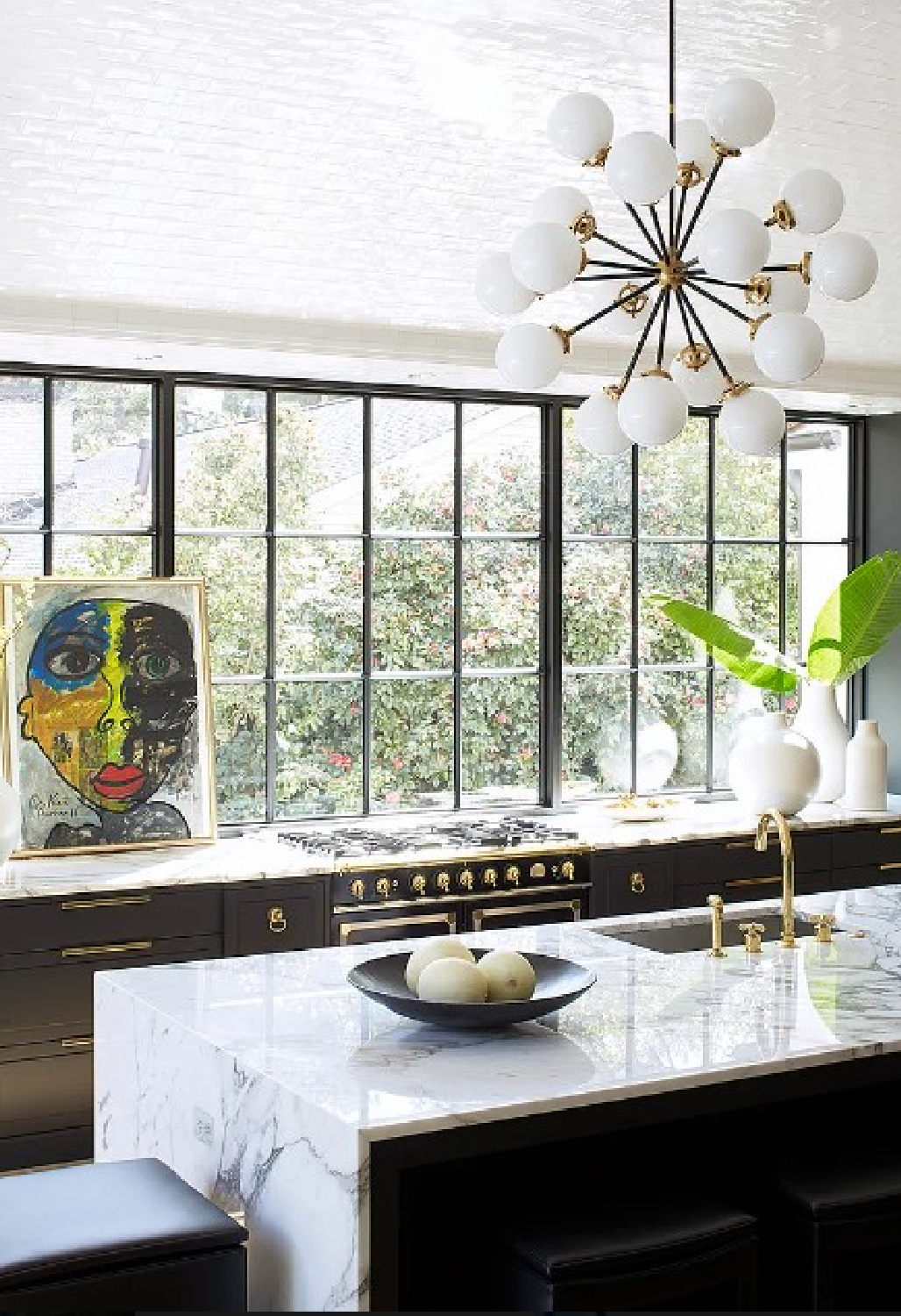 Black kitchen cabinets and white marble counters with French range and gold hardware.