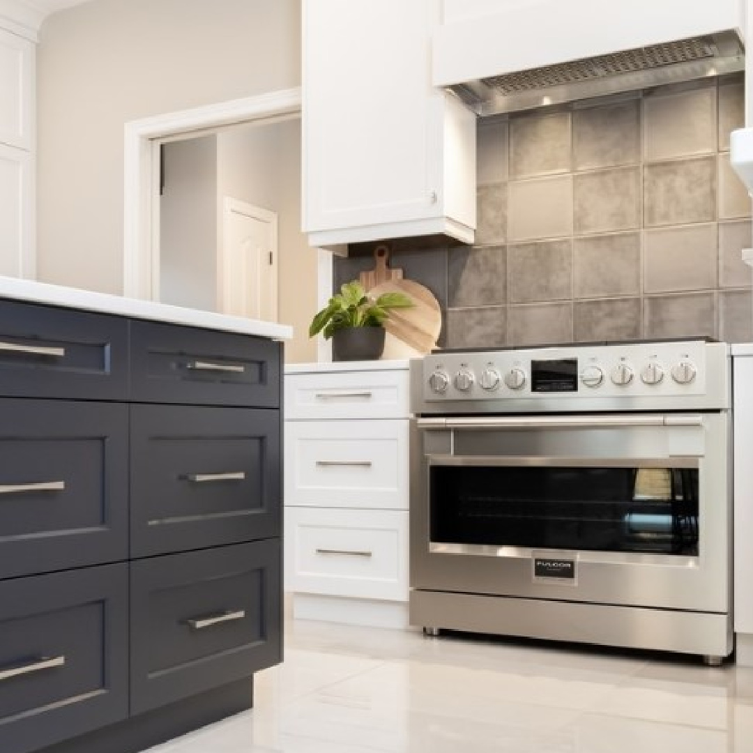 White kitchen by Oak Barrel Cabinetry with grey backsplash tile, stainless range, black island, and BM Decorator's White paint color. #decoratorswhite #bmdecoratorswhite