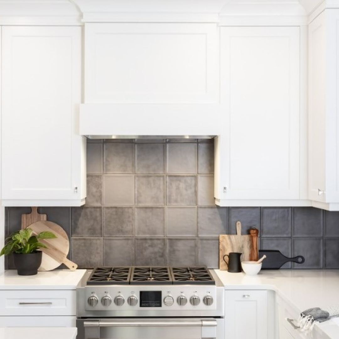 White kitchen by Oak Barrel Cabinetry with grey backsplash tile, stainless range, black island, and BM Decorator's White paint color. #decoratorswhite #bmdecoratorswhite