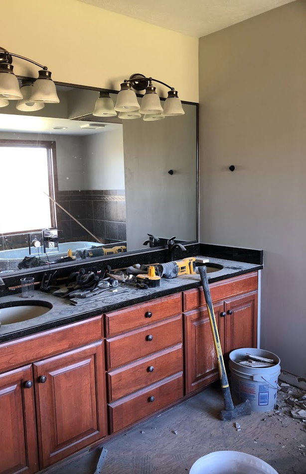 The primary bath before renovation - dark brown vanity, dark brown granite top, and tons of brown tile - Hello Lovely Studio.